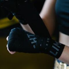 Crop anonymous lady in sportswear using boxing wrap for hand bandaging while training