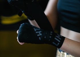 Crop anonymous lady in sportswear using boxing wrap for hand bandaging while training